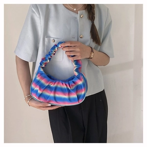 Detail of the pleated rainbow gradient shoulder bag worn over the arm of a model