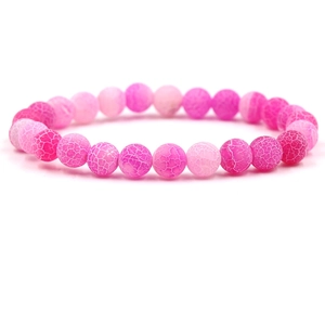 Macro shot of pink gradient beaded bracelet with cracked stone texture on white background