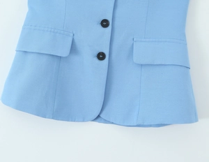 Detailed view of light blue blazer showing black resin buttons and flap pockets
