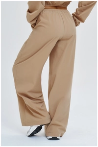 Detail view of khaki wide-leg sports pants featuring elastic high waist and woven fabric