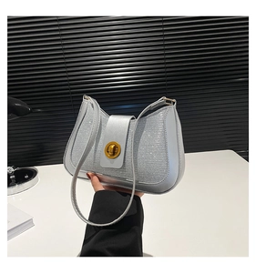 Detail of silver sparkling shoulder bag with golden oval twist lock and shiny sequins