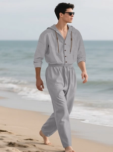 Ensemble en lin gris pour homme avec capuche et détails boutonnés sur une plage ensoleillée
