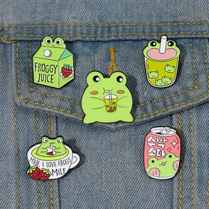 Détail de cinq pin's émaillés grenouille avec lait à la fraise et boba tea sur denim