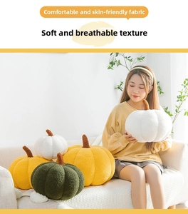 Detail of skin-friendly pumpkin plush pillows in orange and green on a soft sofa