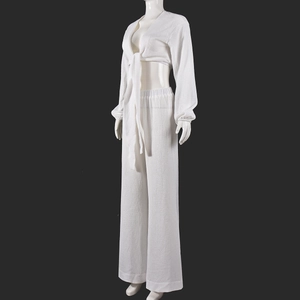 Détail du haut court à nouer blanc et du pantalon plissé large sur un mannequin