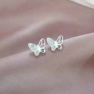 Macro view of butterfly stud earrings in silver steel with white shell inlays