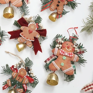 Handmade gingerbread man Christmas ornament with pine needles, red bow and golden bell decoration