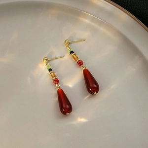 Macro view of vintage beaded gold earrings with multi-color beads and teardrop pendant