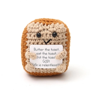 Detail of crochet toast toy holding card with humorous quote on white background