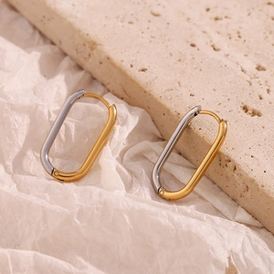 Detailed view of minimalist oval two-tone earrings in gold and silver finish on stone