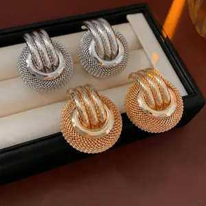Modern metal hollow round stud earrings in gold and silver finish on black velvet