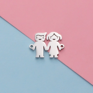 Polished silver boy and girl charms on pink and blue background for DIY jewelry