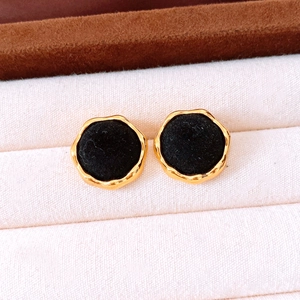 Macro view of vintage gold-trimmed round earrings with black velvet inlay in a box