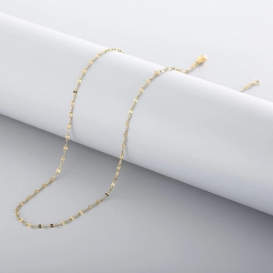 Detailopname van de sprankelende gouden lippenketting op een witte ronde standaard