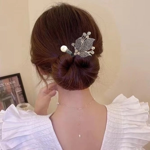 Détail d'un pic à cheveux en forme de nœud argenté avec zircons et perles sur chignon
