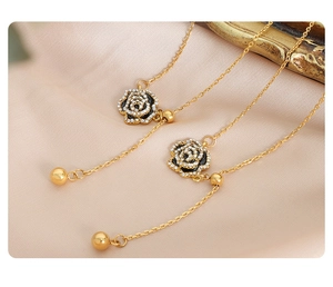 Detail of gold rose earrings with black petals and crystals on pink silk fabric