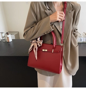 Sac à main rouge tendance avec détail en soie et bandoulière porté par un mannequin chic