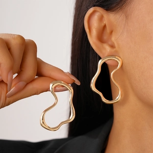 Detailed view of minimalist irregular wavy gold stud earring on model with polished finish