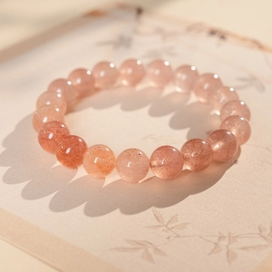 Close-up of translucent strawberry crystal bracelet with natural warm pink stone beads