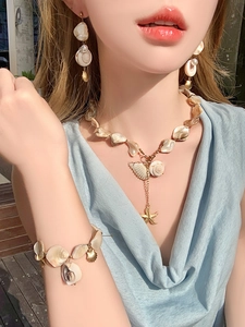 Close-up of ocean-style jewelry set with starfish pendants and irregular pearls on a model
