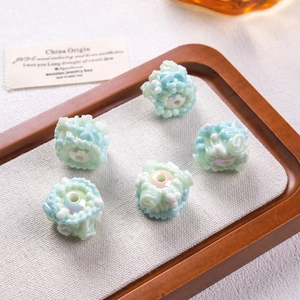 Macro shot of handcrafted flower-shaped oil beads in light blue and white on wooden tray