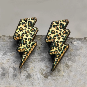 Ethnic lightning earrings featuring sparkly gold leopard print on a grey stone background