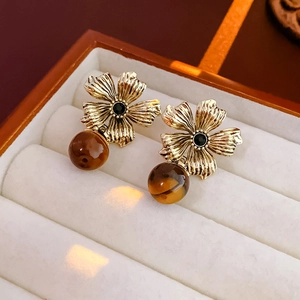 Détail de boucles d'oreilles vintage fleurs avec œil de tigre dans un écrin en velours