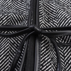 Close-up of black and white herringbone coat with leather bow belt and stitching detail