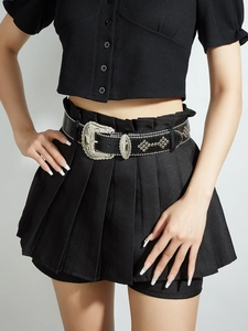 Detail of vintage black leather belt with ornate silver rhinestone buckle and metal studs