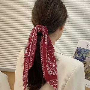Red paisley print hair scarf scrunchie tied on a ponytail in a natural lifestyle setting