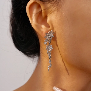 Detail of silver floral drop earrings with rhinestones on a model in close-up view