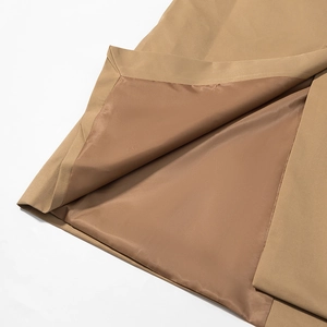 Detailed close-up of khaki trench coat showing premium woven fabric and satin lining