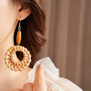 Détails de boucles d'oreilles rondes en rotin tressé avec perle ambre sur un modèle