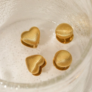 Textured gold heart and round stainless steel stud earrings set in a clear glass jar