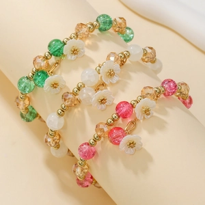 Ensemble de trois bracelets en perles de cristal colorées avec pendentifs fleurs blanches
