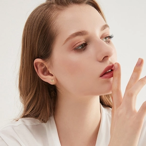 Close-up of elegant gold ball stud earrings worn by a model in a minimalist style