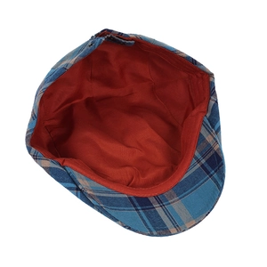 Detail of classic plaid newsboy cap showing contrast red lining and cotton fabric texture