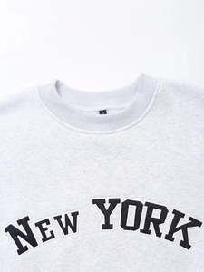 Close-up of New York embroidery on a grey cotton fleece sweatshirt with crew neck detail
