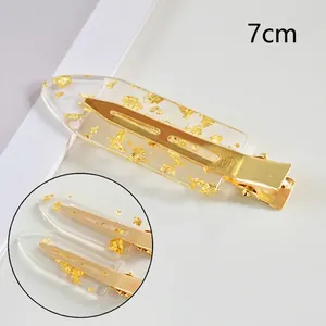 Detail view of a 7cm transparent resin hair clip with gold foil flakes and metal base