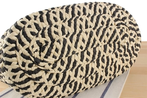 Detailed macro view of woven straw shoulder bag featuring black and beige herringbone patterns