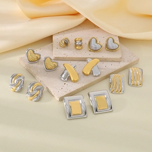 Two-tone 18K gold plated heart and geometric earrings on beige stone display