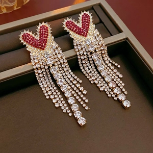 Detail of gold heart earrings with red rhinestones and crystal tassels in a box
