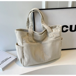 Détail du sac cabas en velours côtelé blanc cassé montrant les poches avant et la texture