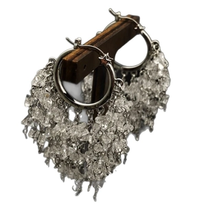 Elegant silver hoop earrings with long crystal tassel fringe on a wooden display stand
