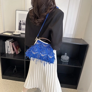 Blue vintage evening bag with sequins and long tassels carried by a model in a blazer