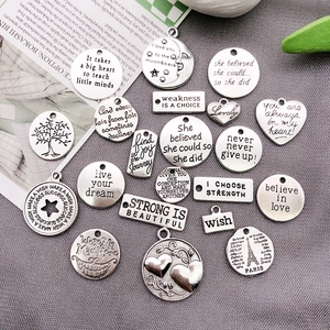 Macro detail of assorted antique silver alloy charms with engraved English inspirational quotes