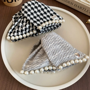 Close-up of tweed triangle shark hair clip with pearls and engraved metal plate