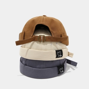 Detail of canvas docker hats with adjustable metal buckle and heart patch in multi-colors