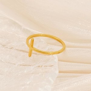 Macro shot of minimalist gold stainless steel ring with vertical bar on white fabric
