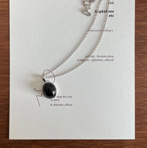 Detail of 925 sterling silver necklace with a polished black onyx oval pendant on paper